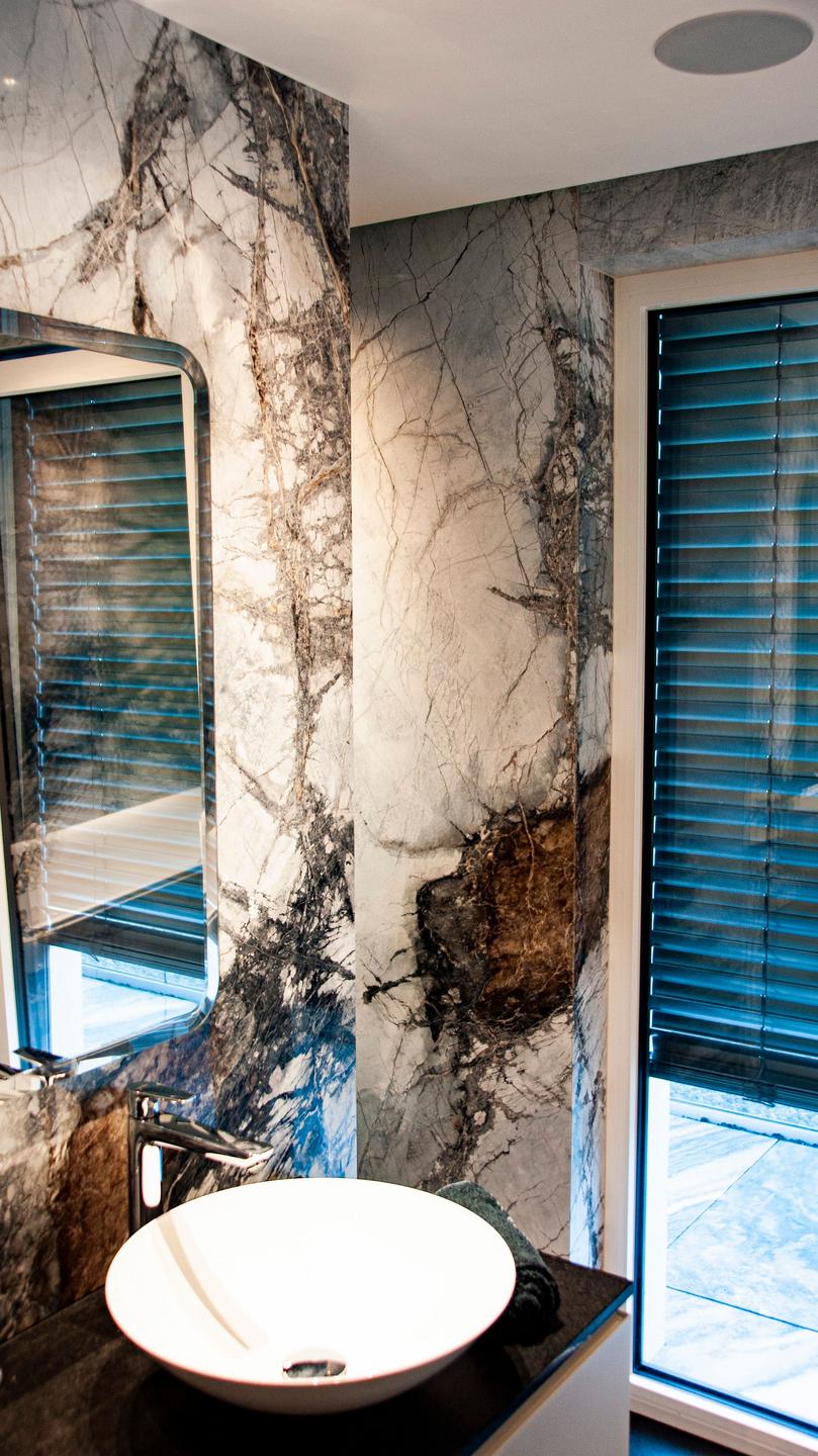 Badezimmer mit Natursteinwänden und Waschtisch aus Marmor
