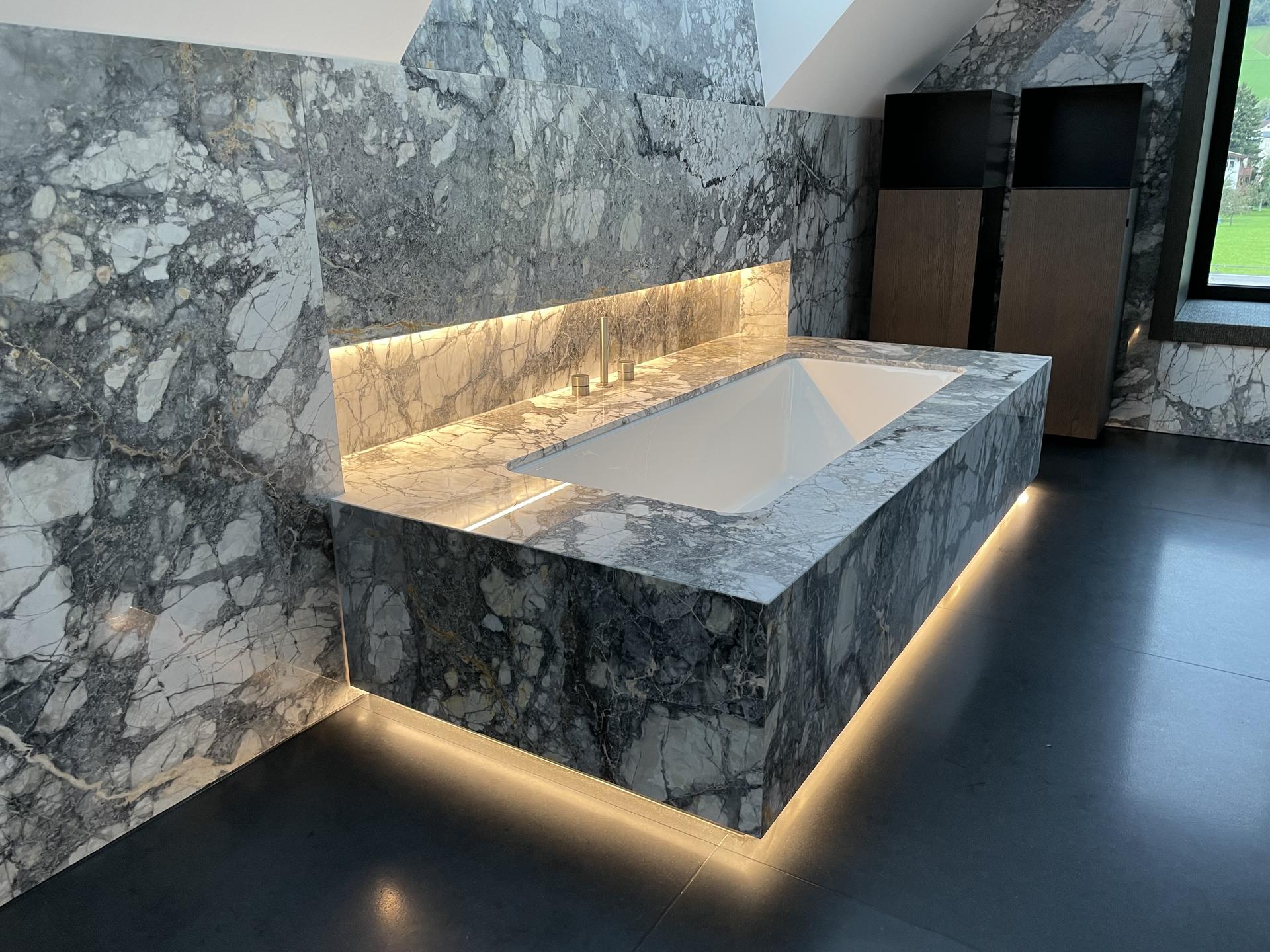Freistehende Badewanne vor einer Natursteinwand