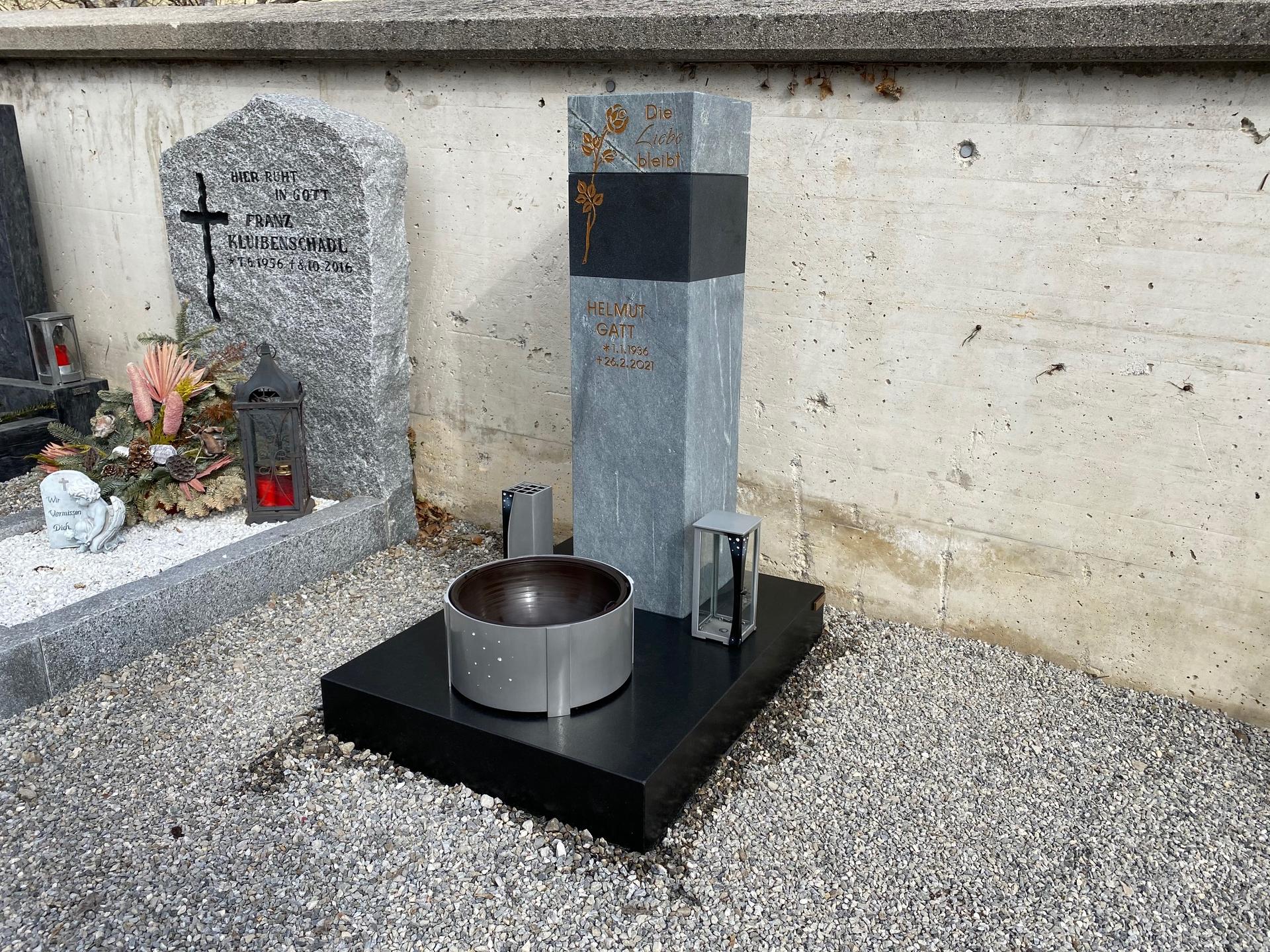 Grabstein mit Skulptur und Grabschmuck